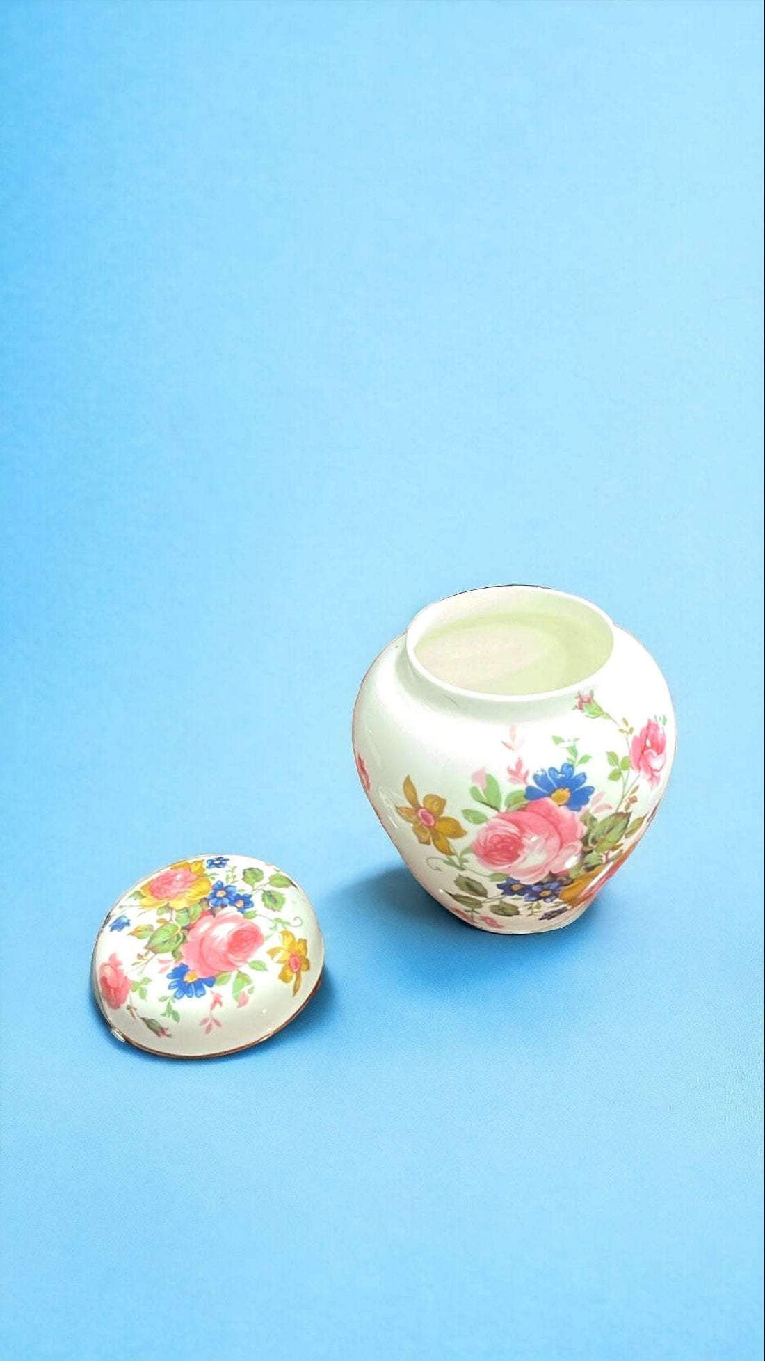 Tibor antiguo pintado a mano con motivos florales elegantes sobre fondo urbano. Decoración ideal para interiores clásicos o vintage.