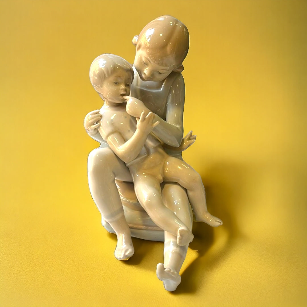 Figura de porcelana Hermanos Jugando de Lladró, representando a dos niños en un momento tierno. Elegancia y calidad para la decoración del hogar.