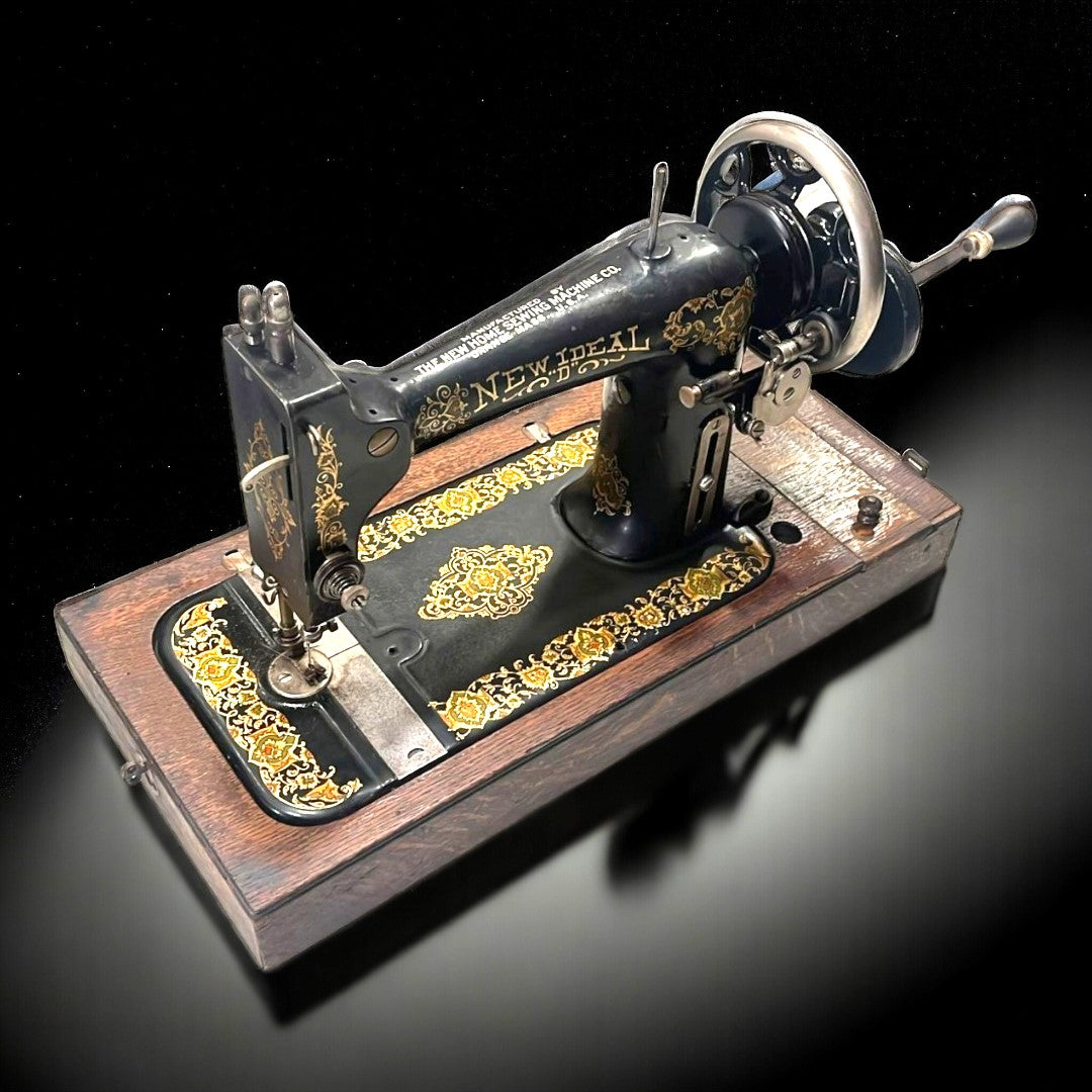 Máquina de coser portátil New Ideal de 1846 con detalles dorados y base de madera, ideal para coleccionistas y decoración vintage.