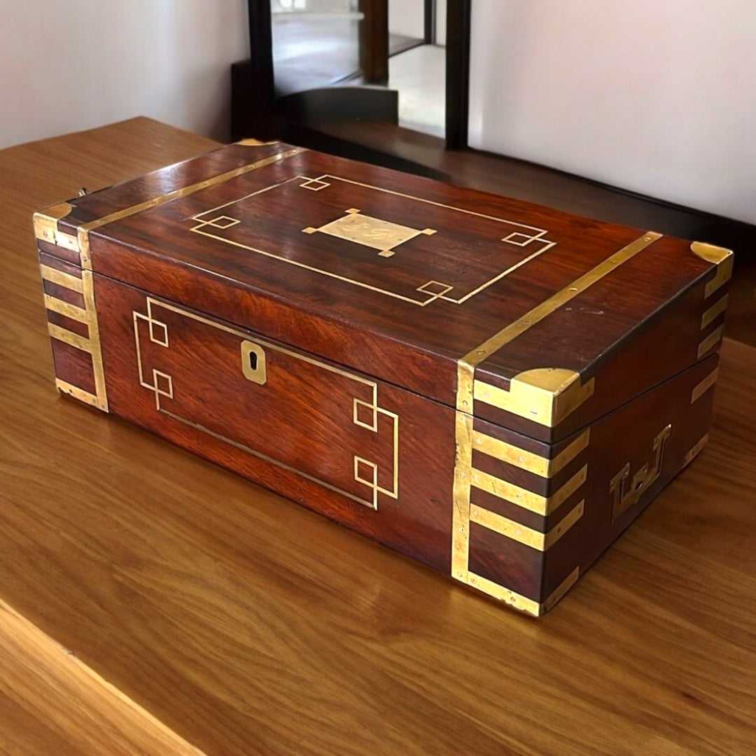 Escritorio de Campaña de caoba con detalles en latón, diseño rectangular y acabado brillante. Decoración funcional con historia del siglo XIX.