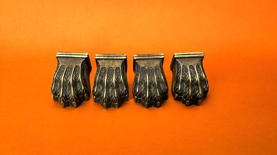 Juego de cuatro garras de bronce para patas de mesa, con diseño elegante y detallado, sobre fondo marrón. Aporta estilo y durabilidad a tus muebles.