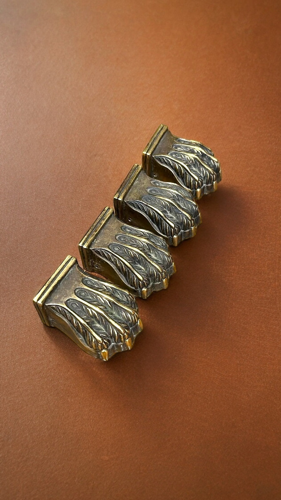 Juego de cuatro garras de bronce para patas de mesa, con diseño elegante y detallado, sobre fondo marrón. Aporta estilo y durabilidad a tus muebles.