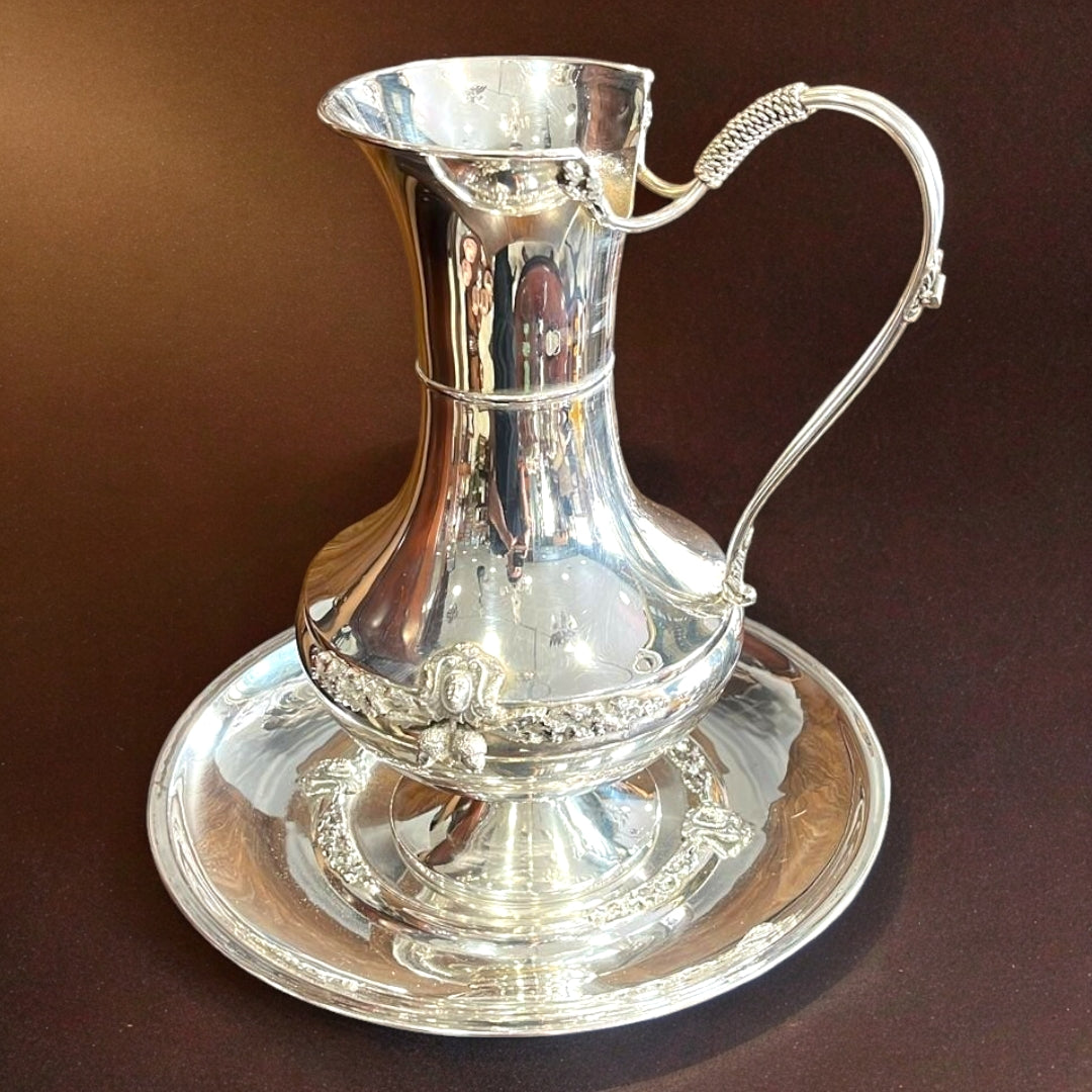 Aguamanil de Meneses con diseño moderno y sofisticado, fabricado en alpaca con acabados decorativos, incluye jarra y palangana.