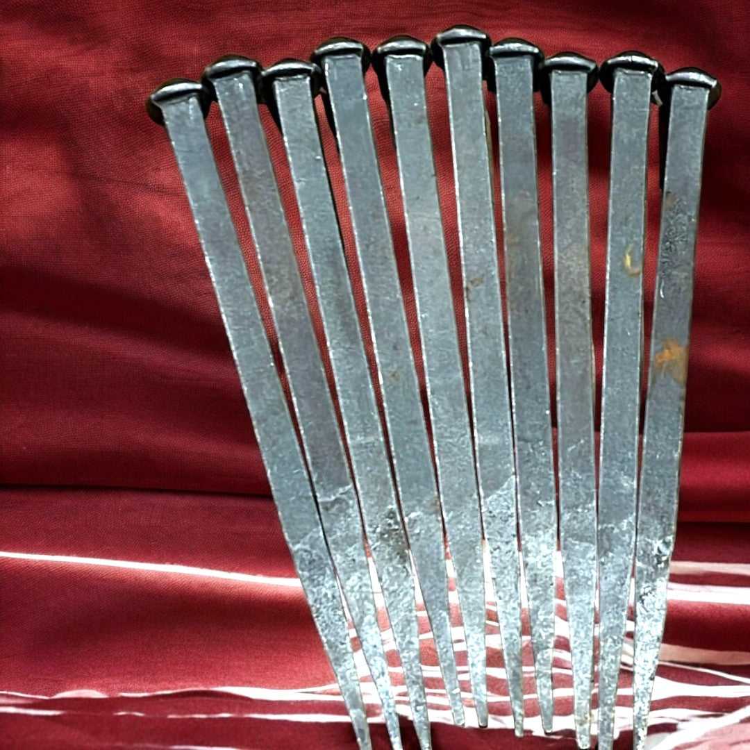 Conjunto de clavos antiguos elegantes de hierro alineados sobre tela roja, perfectos para decoración vintage y restauración artesanal.