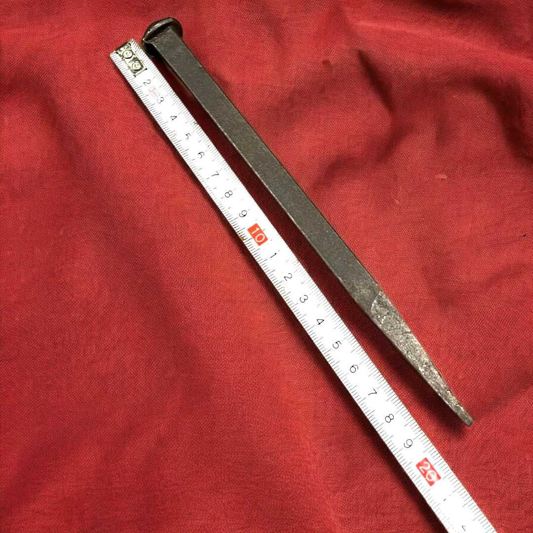 Clavo grande antiguo de hierro medido con cinta métrica, mostrando su tamaño ideal para proyectos de decoración y restauración.