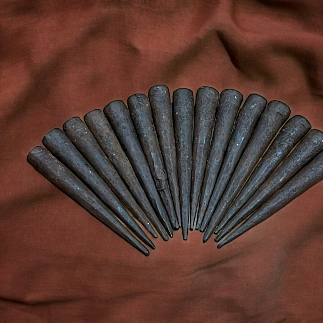 Clavos Sin Cabeza antiguos dispuestos en abanico sobre tela marrón. Ideales para decoraciones rústicas y restauraciones históricas.