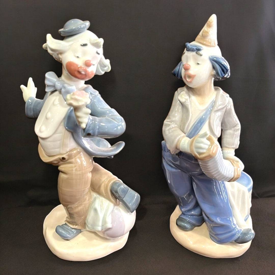 Figuras de porcelana Nao-Lladró: Payaso con flor y Payaso con acordeón en tonos pastel, ideales para decoración de interiores elegantes.