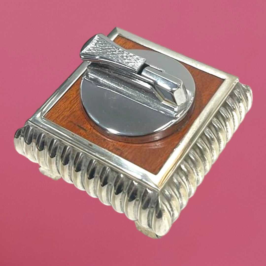 Mechero Escritorio en metal plateado con diseño cuadrado y detalles en madera, ideal para decoración elegante en oficina o sala.