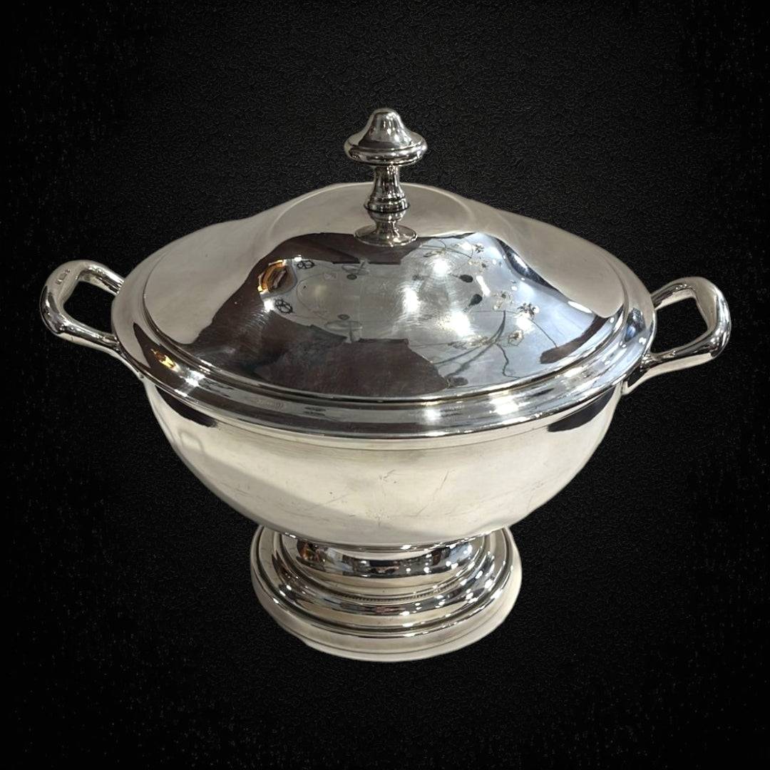 Sopera clásica de metal plateado, elegante y decorativa, con tapa desmontada y asas laterales, ideal para decoración de mesa sofisticada.