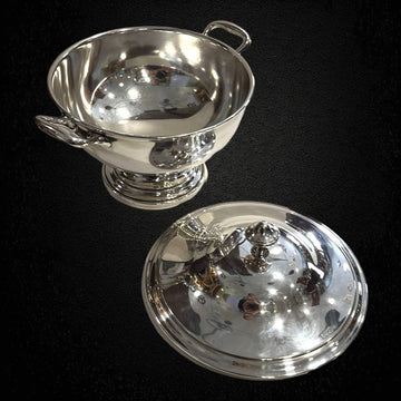 Sopera clásica de metal plateado, elegante y decorativa, con tapa desmontada y asas laterales, ideal para decoración de mesa sofisticada.