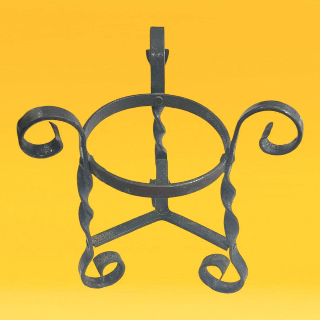 Macetero de hierro forjado decorativo con diseño de espirales, ideal para plantas pequeñas en interiores o jardines.
