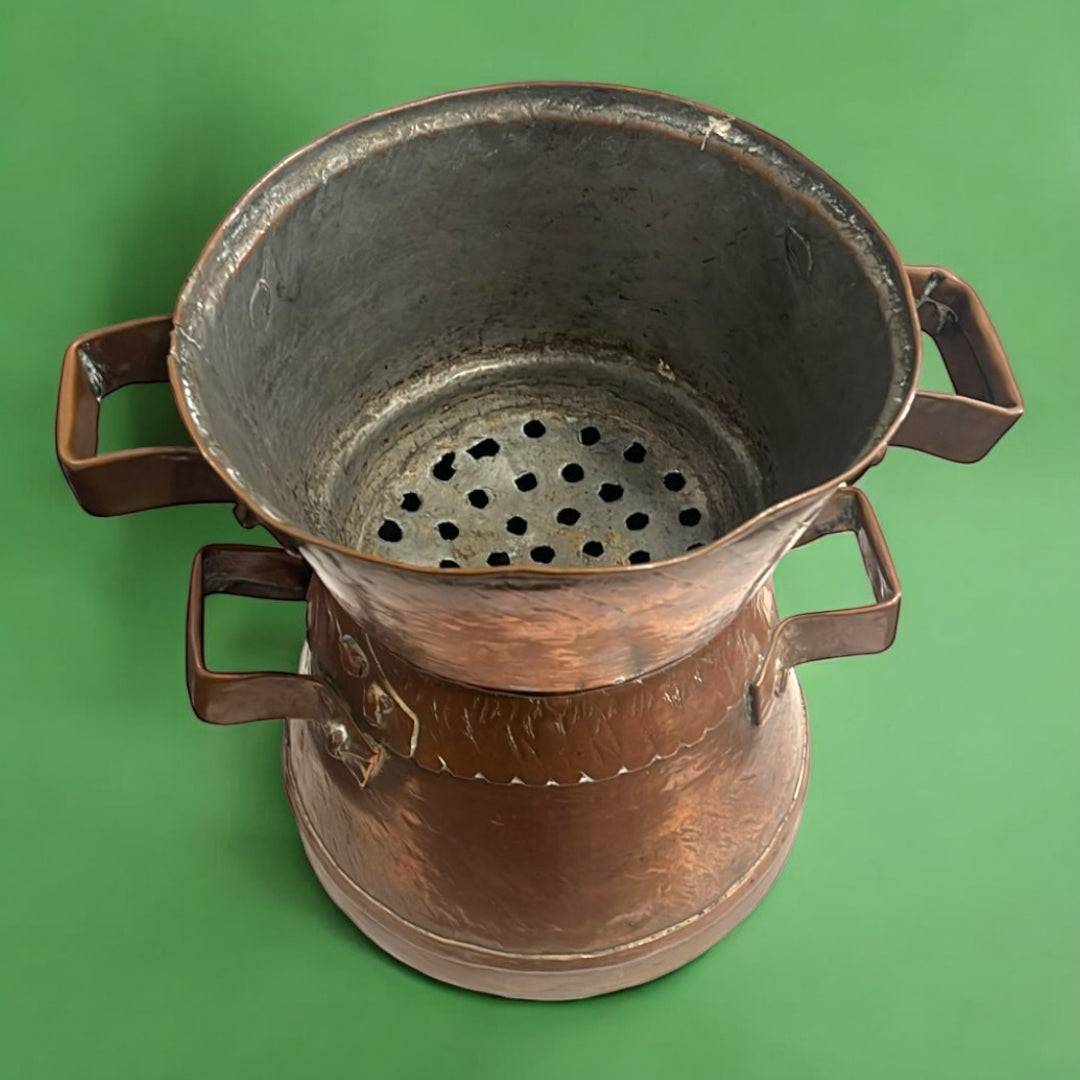 Antiguo cocedero de cobre con asas dobles y base perforada, ideal para decoración vintage en cocinas rústicas. Pieza única de elegancia artesanal.