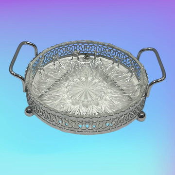 Entremesera de metal plateado y cristal con asas laterales sobre fondo degradado. Diseño clásico ideal para decoración de eventos elegantes.