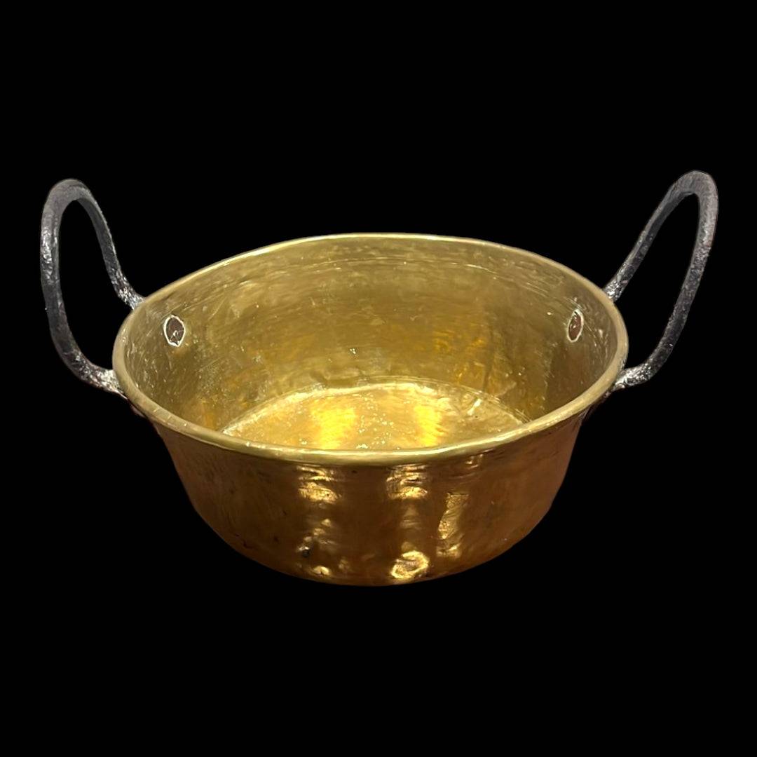 Caldero de metal antiguo con asas de hierro forjado, ideal para decoración vintage en interiores rústicos. Pieza única con acabado brillante.