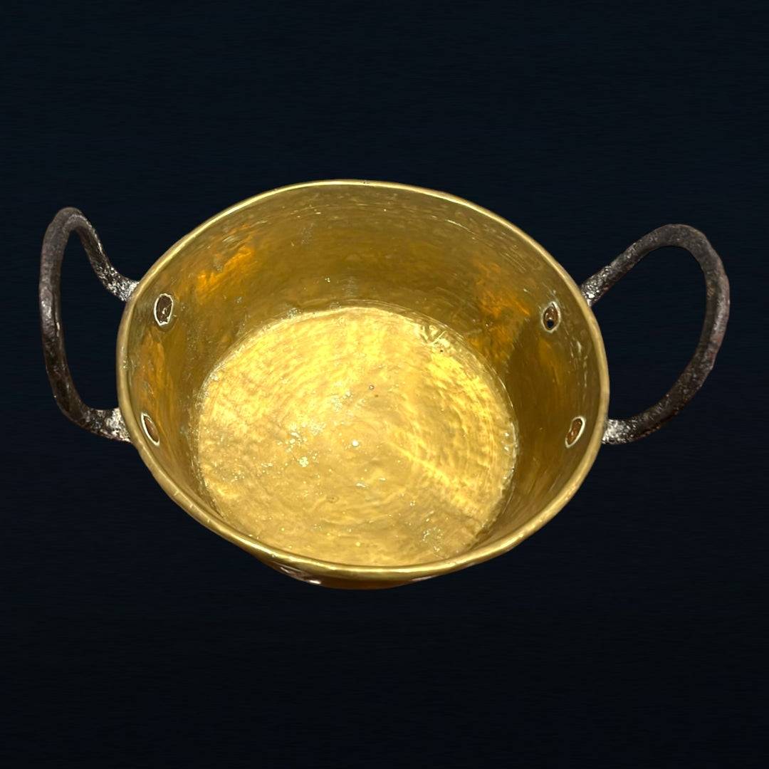 Caldero de metal antiguo con asas de hierro forjado, ideal para decoración vintage en interiores rústicos. Pieza única con acabado brillante.