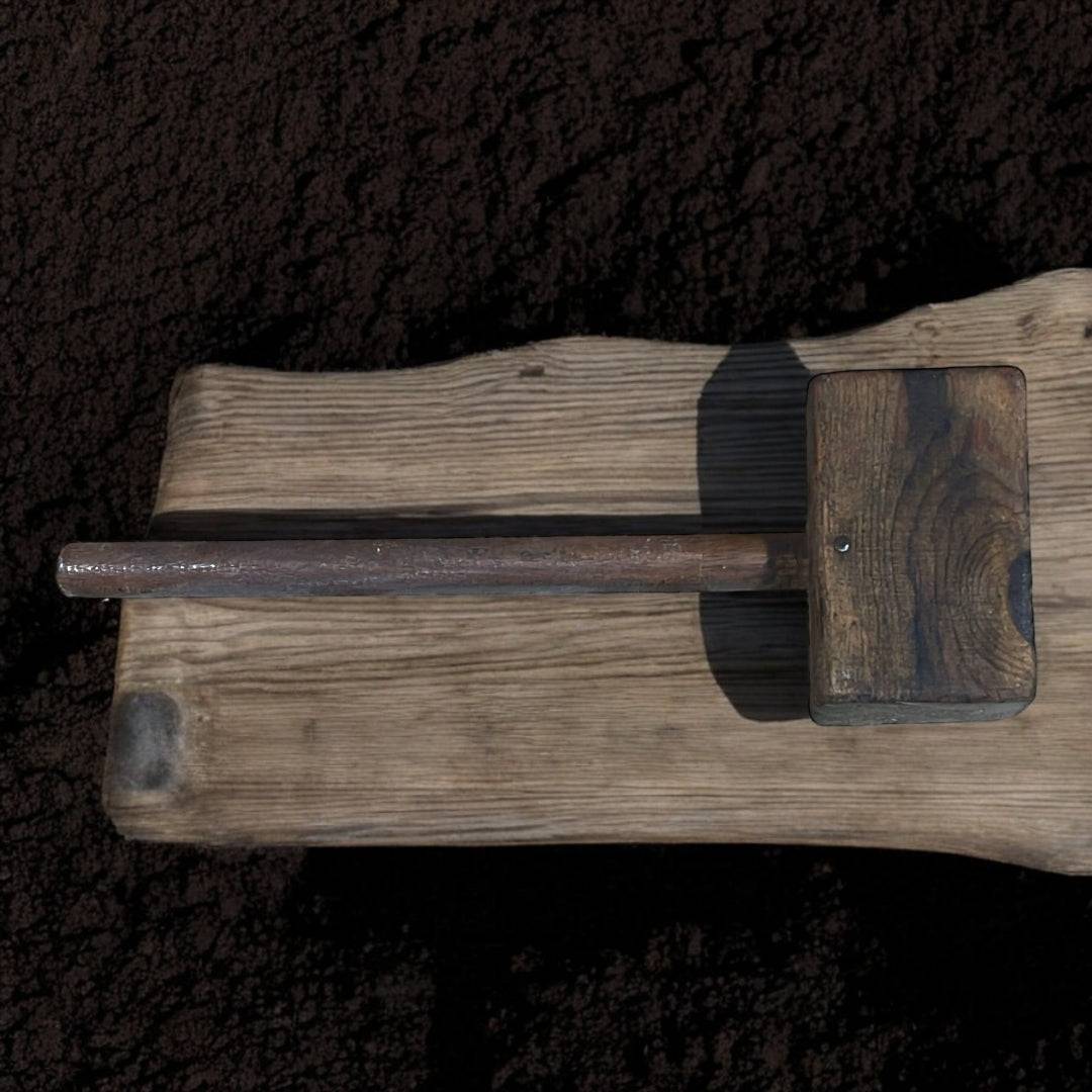 Antiguo mazo de madera rústico sobre tierra seca, pieza única y decorativa ideal para estilos vintage e industriales en decoración de hogar.