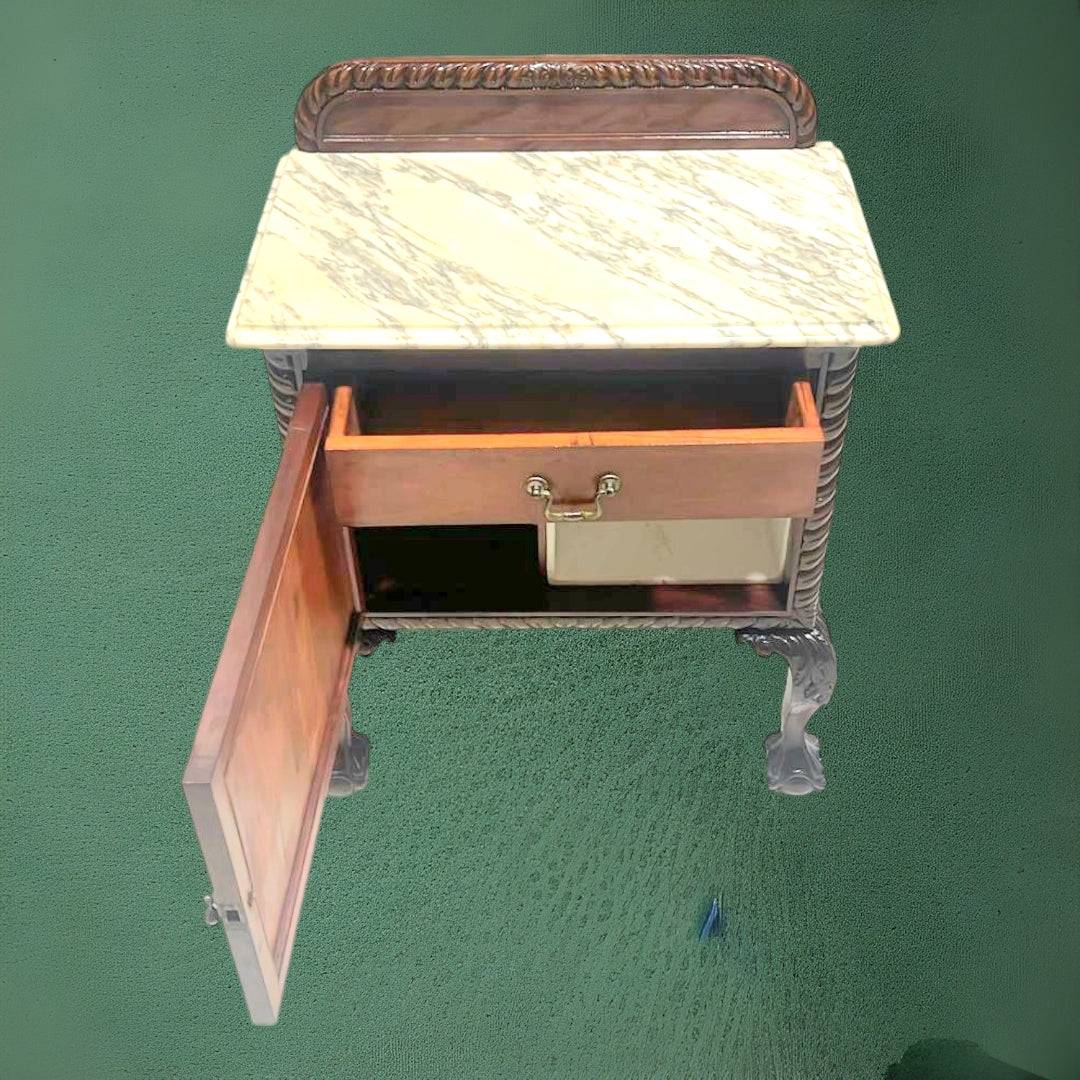 Mesita de noche antigua con tapa de mármol, elegante y funcional, con patas talladas y acabado en madera oscura. Ideal para decoración vintage de dormitorio.