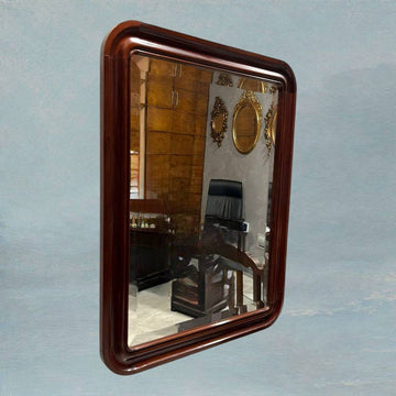 Espejo vintage con marco de caoba, estilo y elegancia atemporal, colgado en pared azul con reflejo de oficina clásica. Ideal para decoración de interiores.