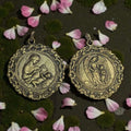 Medallas de metal fundido con relieves religiosos únicos, Virgen con Niño Jesús y Ángel de la Guarda con niña, sobre fondo decorado con flores rosadas.