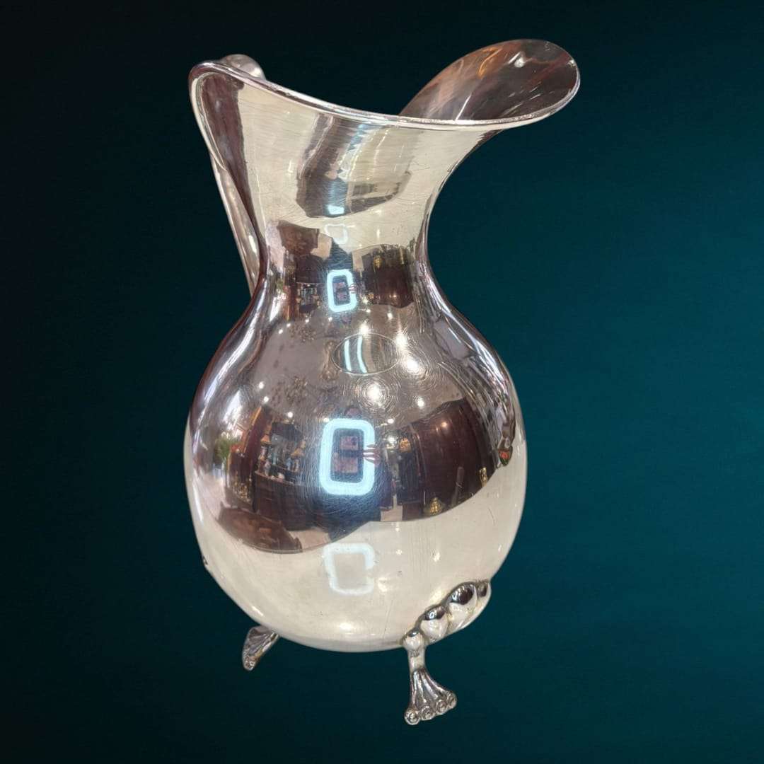 La Jarra de metal plateado es una pieza decorativa que captura la esencia de la elegancia tradicional con un estilo refinado y atemporal. 