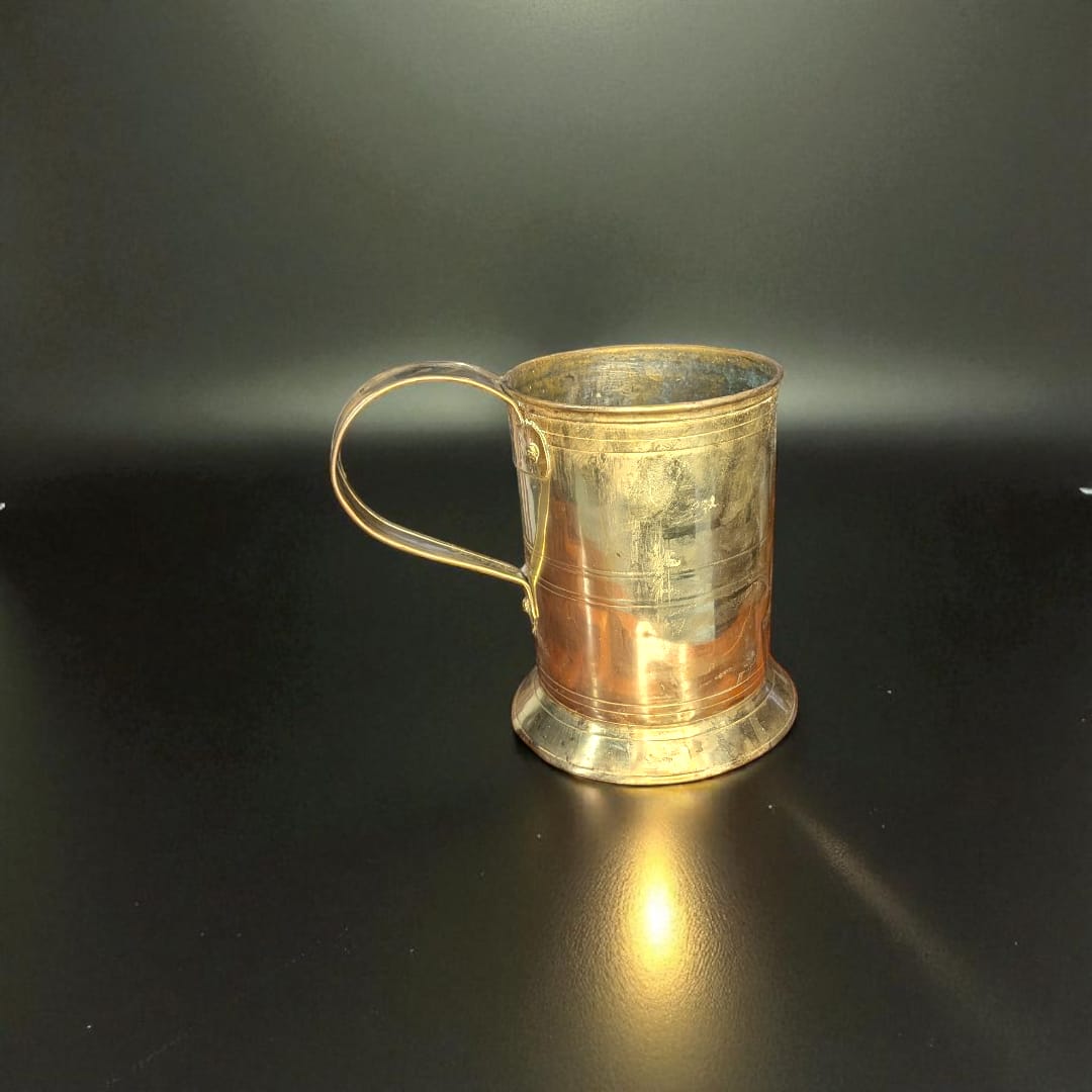 Jarra de Cerveza Alemana en metal vintage coleccionista sobre escritorio con libros antiguos. Decoración ideal para amantes de la cervecería clásica.