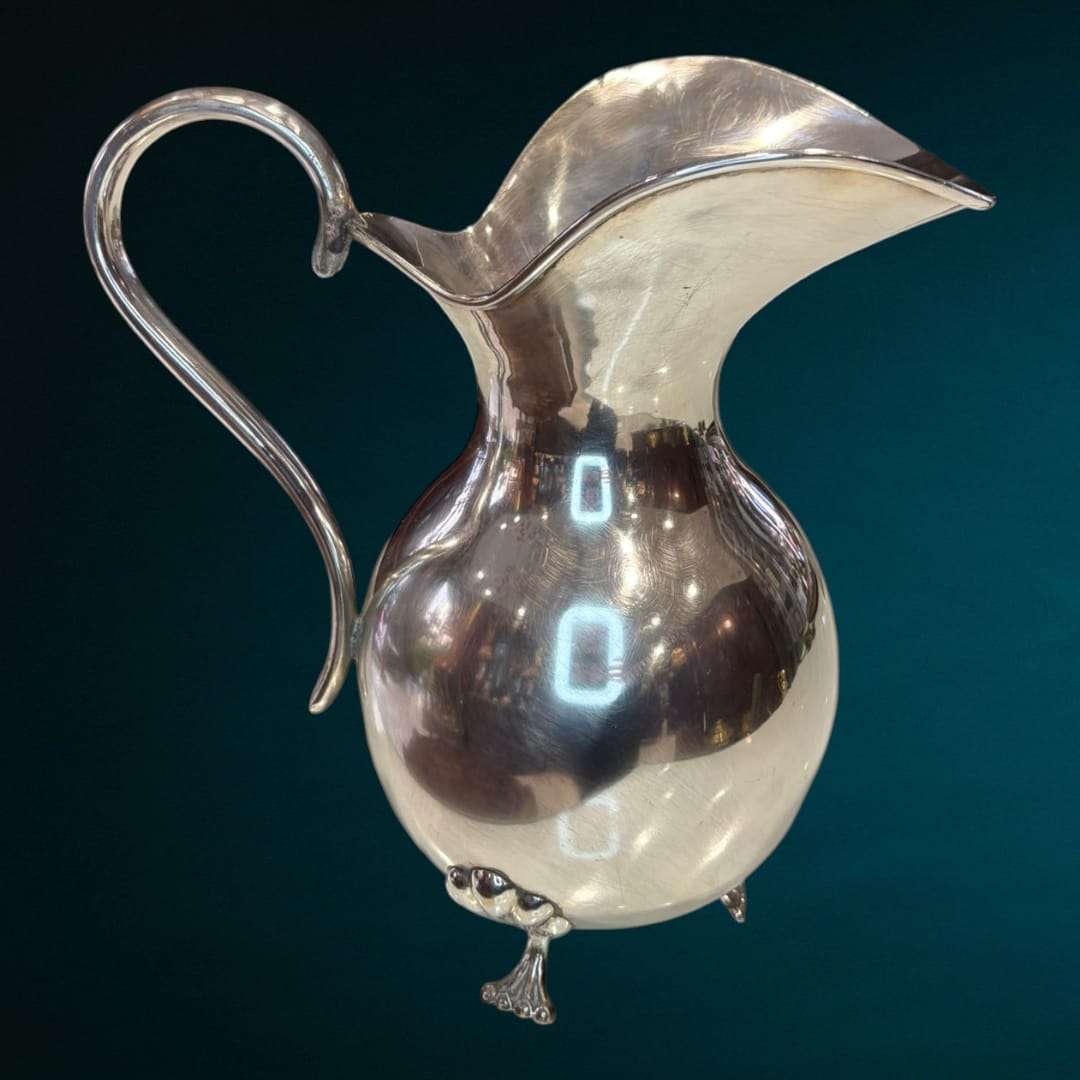 La Jarra de metal plateado es una pieza decorativa que captura la esencia de la elegancia tradicional con un estilo refinado y atemporal. 