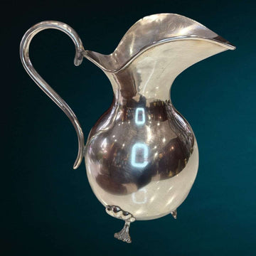 La Jarra de metal plateado es una pieza decorativa que captura la esencia de la elegancia tradicional con un estilo refinado y atemporal. 