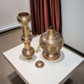 Lampara India antigua de metal y cobre artesanal única, desmontada en tres piezas sobre mesa blanca, con grabados orientales detallados.