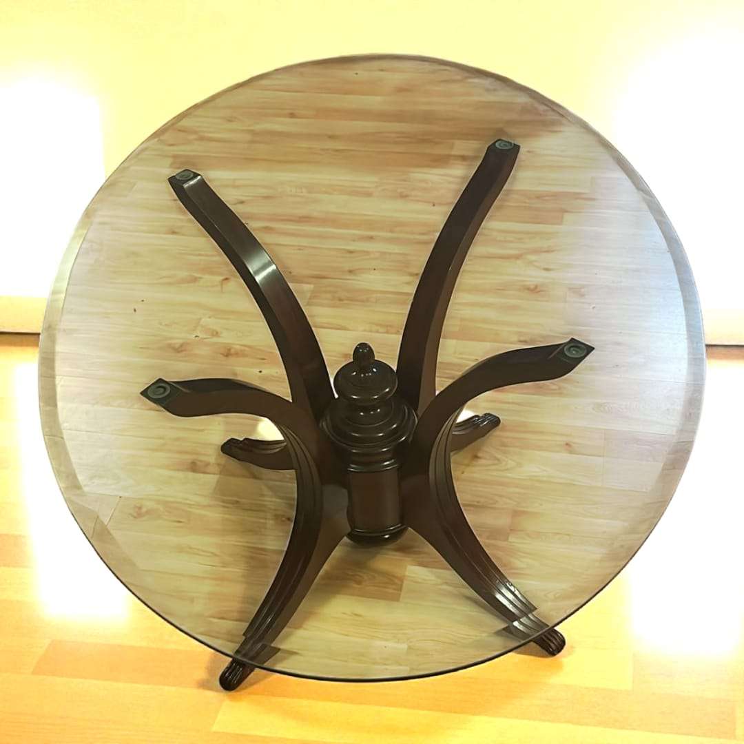 Vista superior de mesa de tapa de cristal con base de caoba. Diseño artístico y funcional para decoración de hogar elegante.