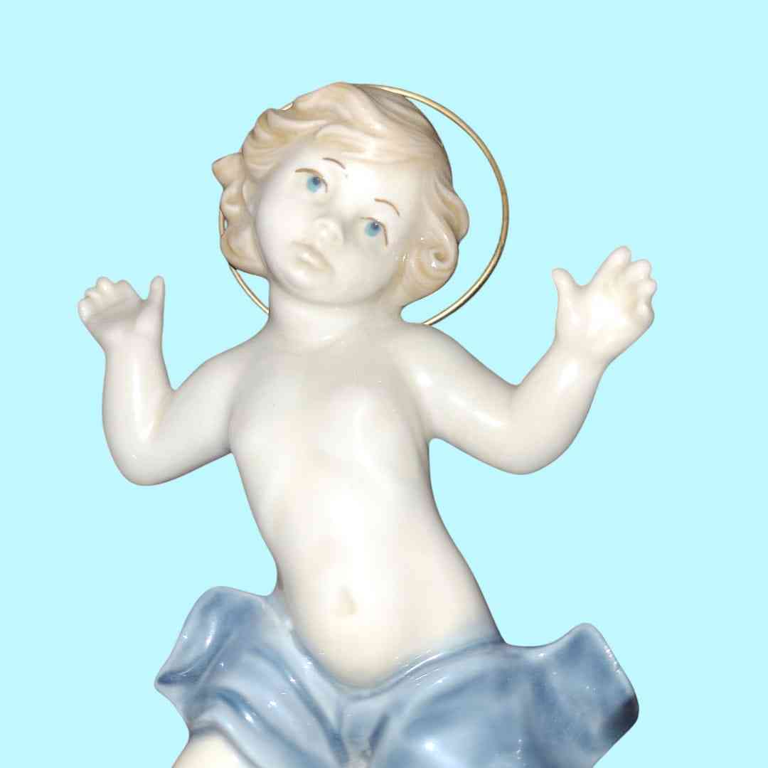 Figura Niño Jesús en porcelana MIRETE, edición limitada, con detalles en azul y halo dorado. Arte sacro para decoración y colección.