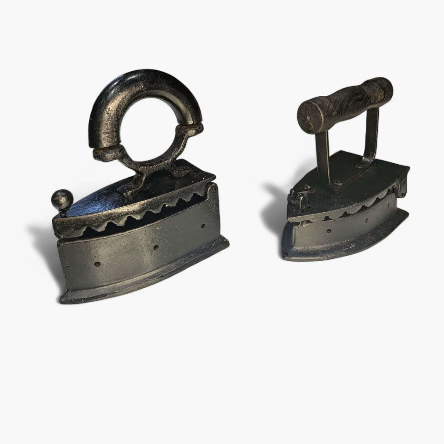 Dos planchas decorativas de fundición con asas diferentes sobre fondo blanco.