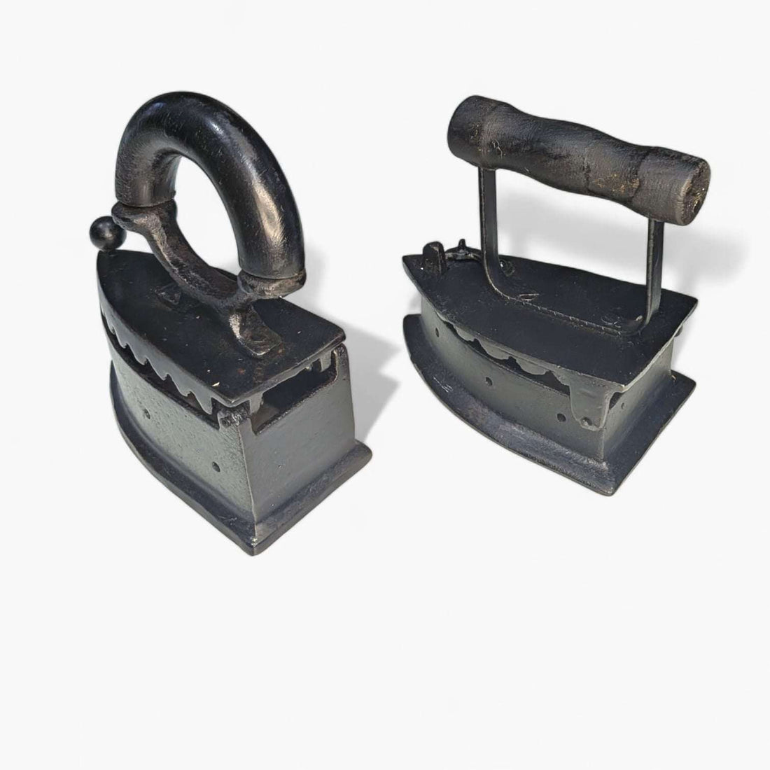 Dos planchas decorativas de fundición con asas diferentes sobre fondo blanco.