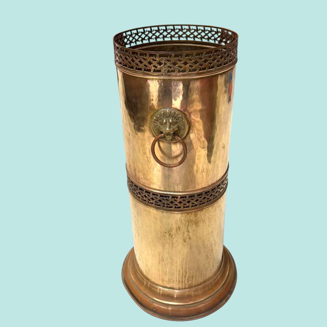 Paragüero de metal dorado con cabeza de león y anilla decorativa.