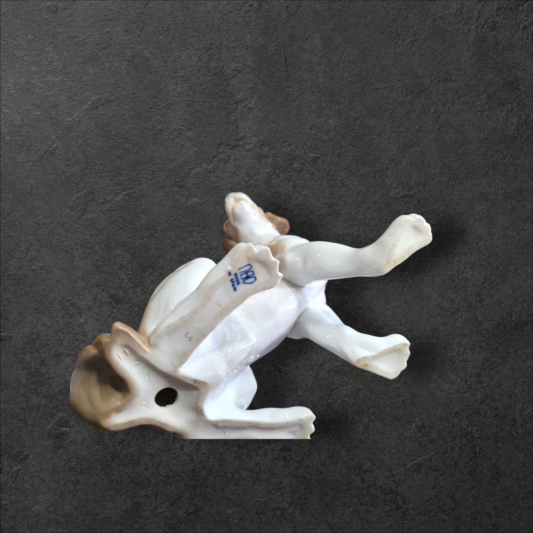Figura de perro manchado en porcelana fina Nao Lladró, diseño bicolor con orejas caídas, ideal para decoración elegante en el hogar.