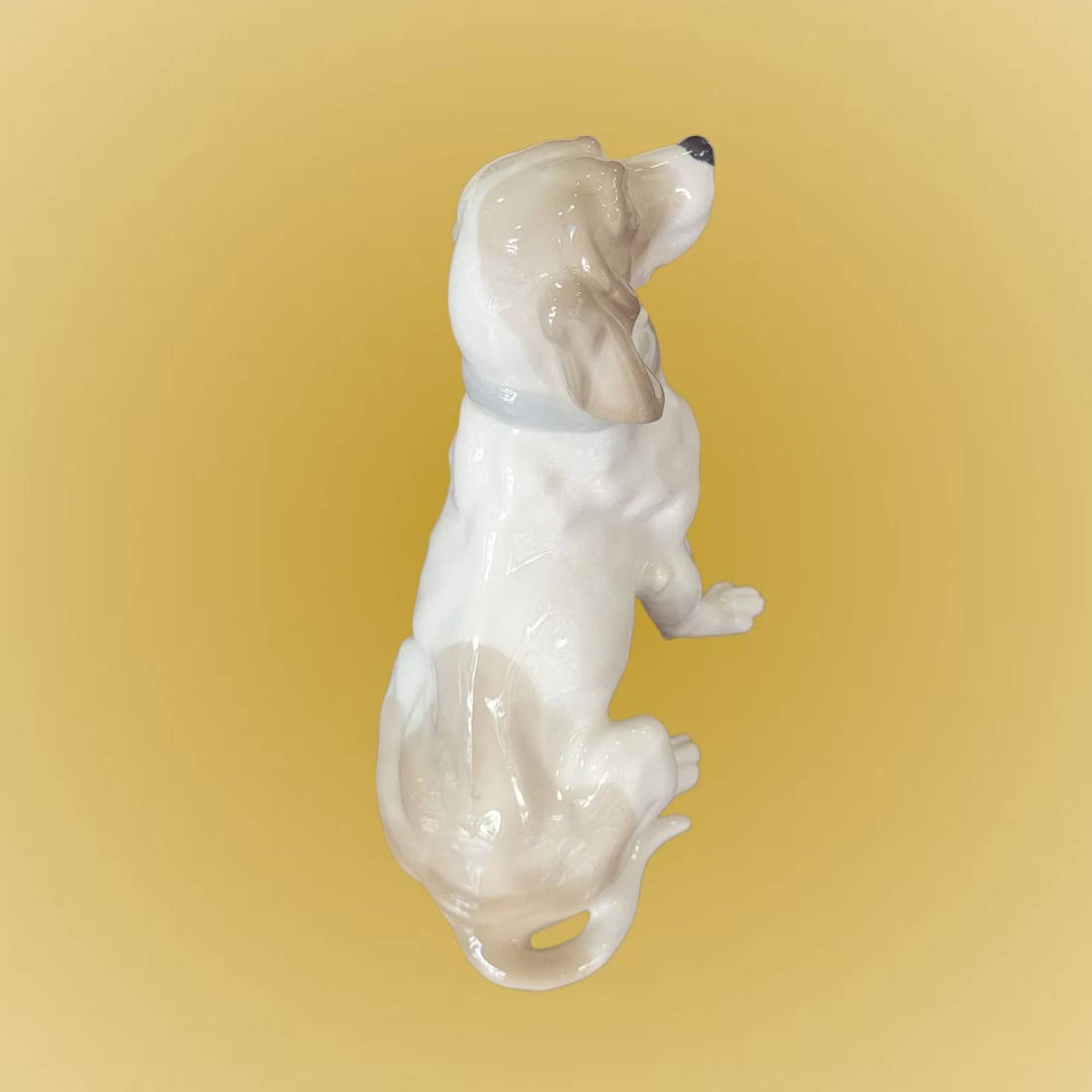 Figura de porcelana de perro Cocker sentado elegante, con detalles realistas y acabado brillante. Ideal para decoración en hogar o colección.