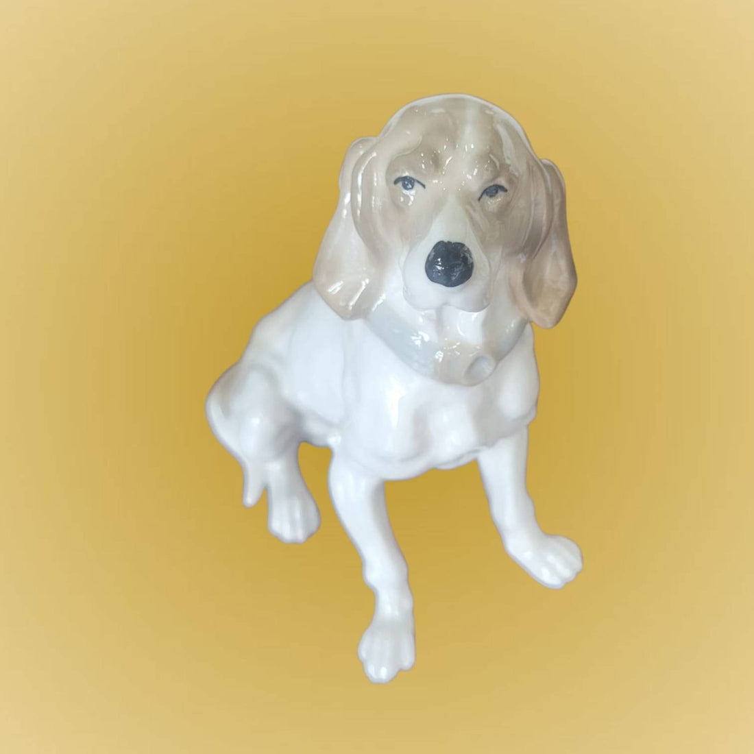 Figura de porcelana de perro Cocker sentado elegante, con detalles realistas y acabado brillante. Ideal para decoración en hogar o colección.