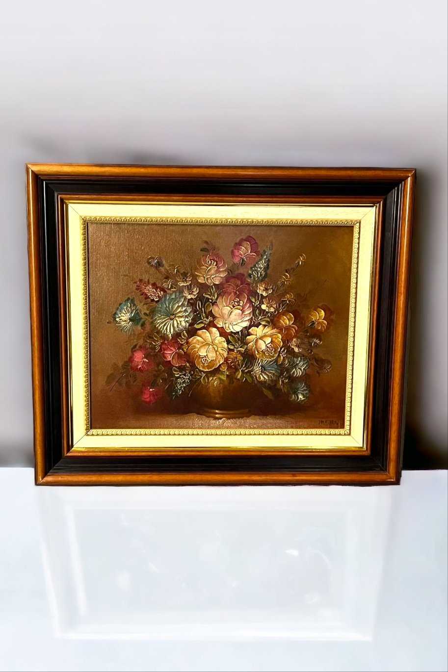 Óleo Floral de Juan Lara con centro floral vibrante en tonos cálidos, enmarcado en elegante marco de tres colores. Arte exclusivo para decoración sofisticada.