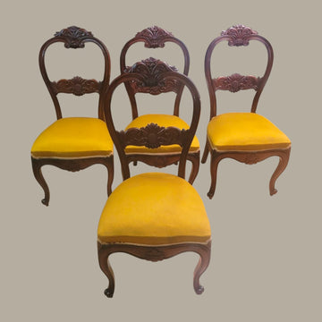 Cuatro sillas estilo Isabelino en madera de caoba con tapizado amarillo.