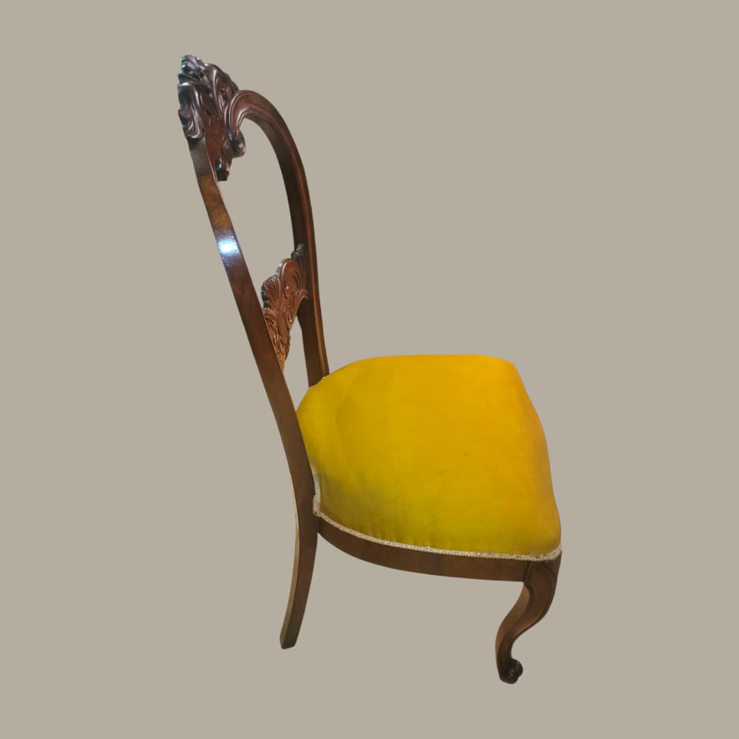 Vista lateral silla vintage estilo Isabelino tapizada en terciopelo amarillo.