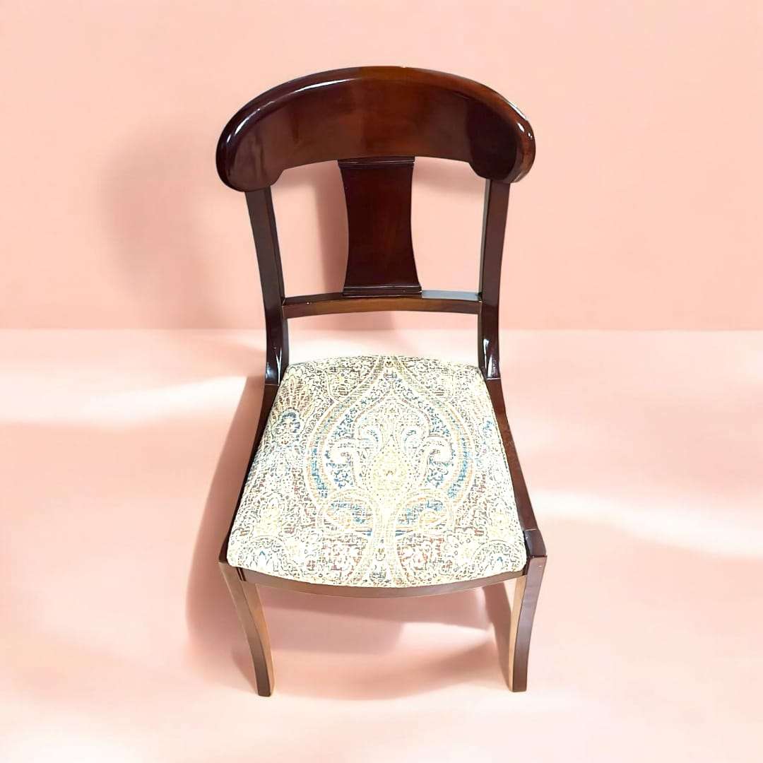Vista frontal individual de una silla de caoba con asiento tapizado en tela clásica, perfecta para ambientes elegantes.