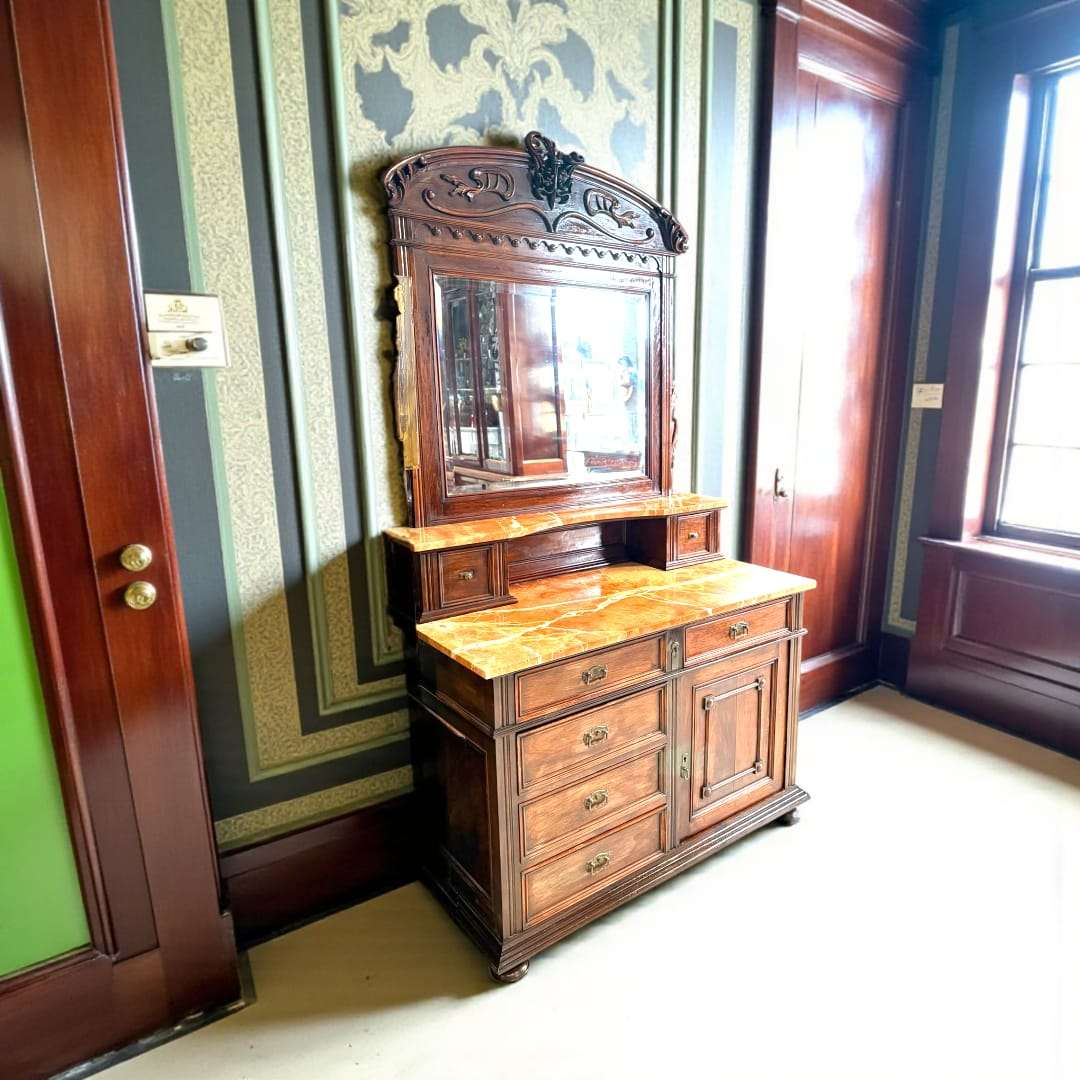 Tocador de caoba con tapa de mármol rojo veteado y espejo biselado.