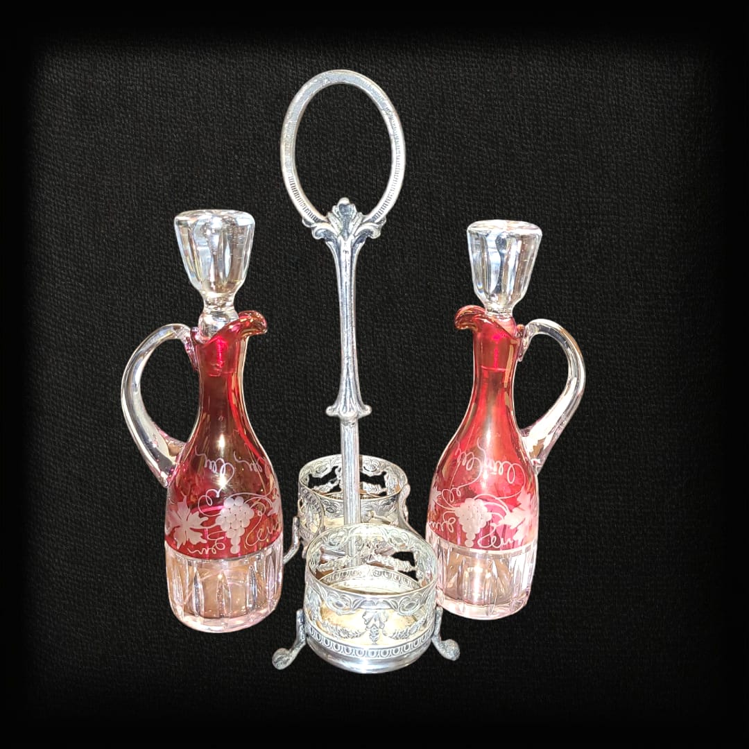Vinagrera antigua con soporte de metal plateado y botellas de cristal rojo grabado. Diseño elegante y clásico para decoración de mesa.