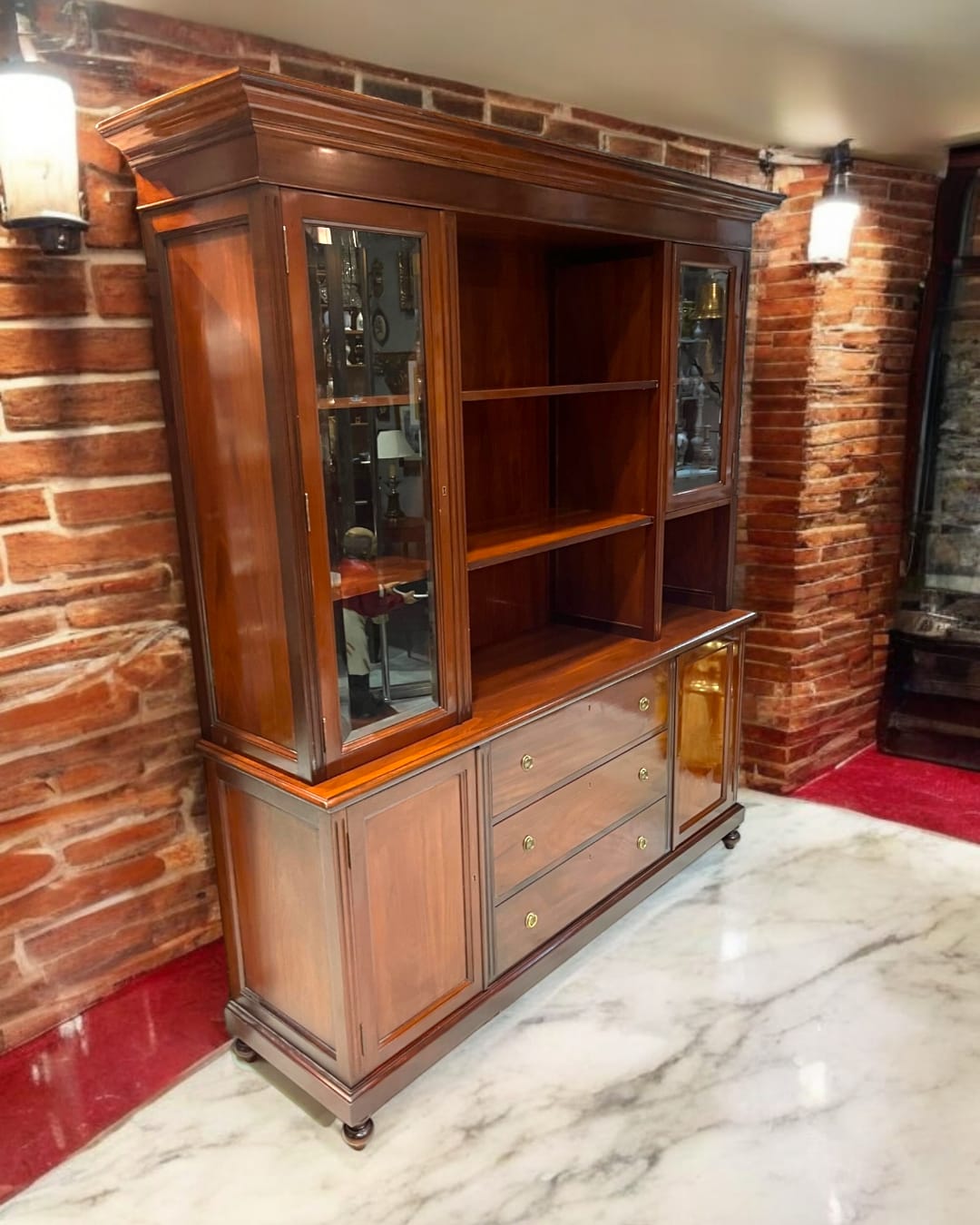 Librería-aparador de caoba maciza con detalles clásicos, ideal para organizar y decorar. Diseño elegante con vitrinas de vidrio y cajones espaciosos.