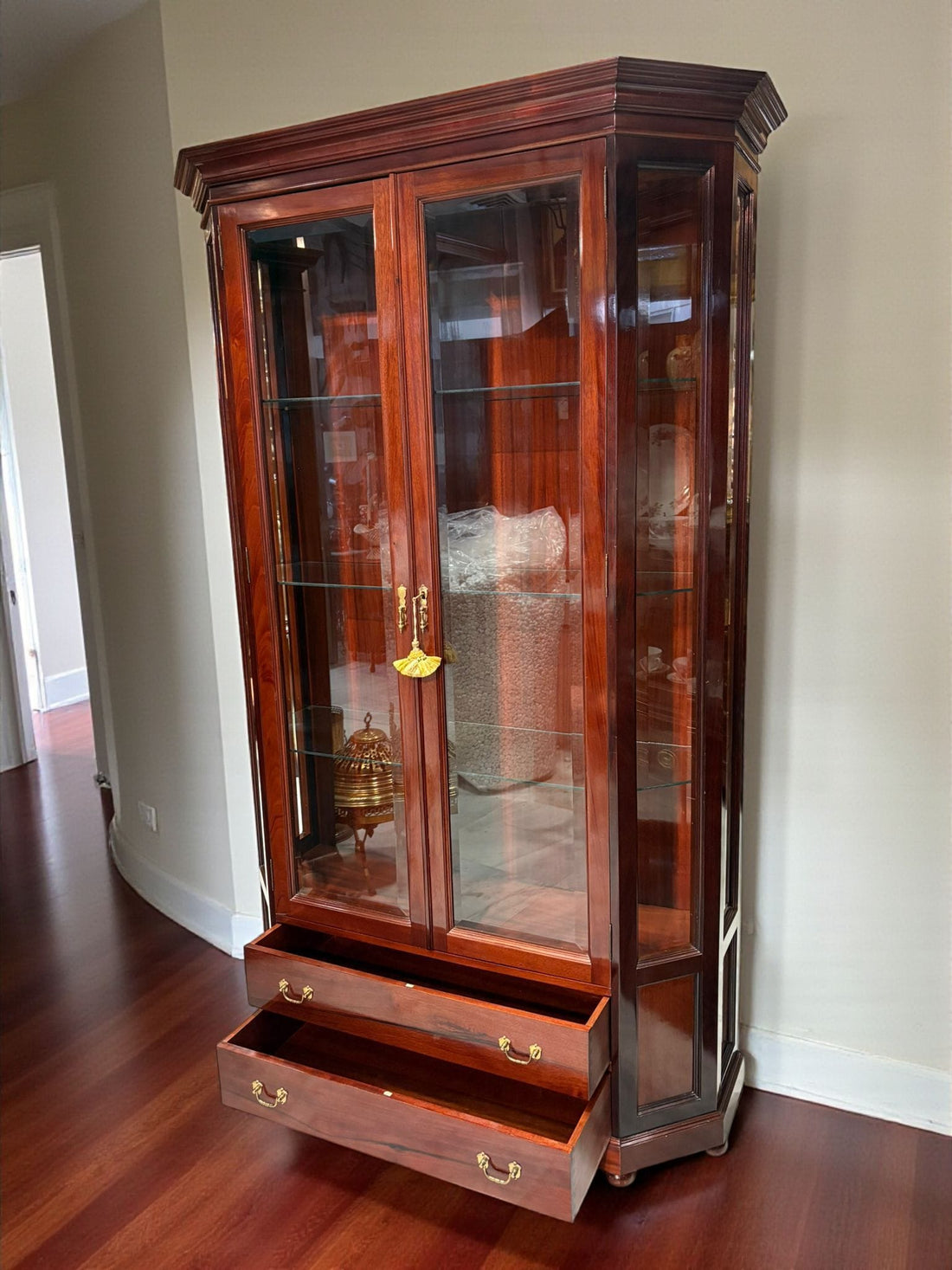 Vitrina de caoba con cristal y cajones – elegancia y distinción, con puertas de vidrio y estantes para exhibir objetos decorativos en interiores.