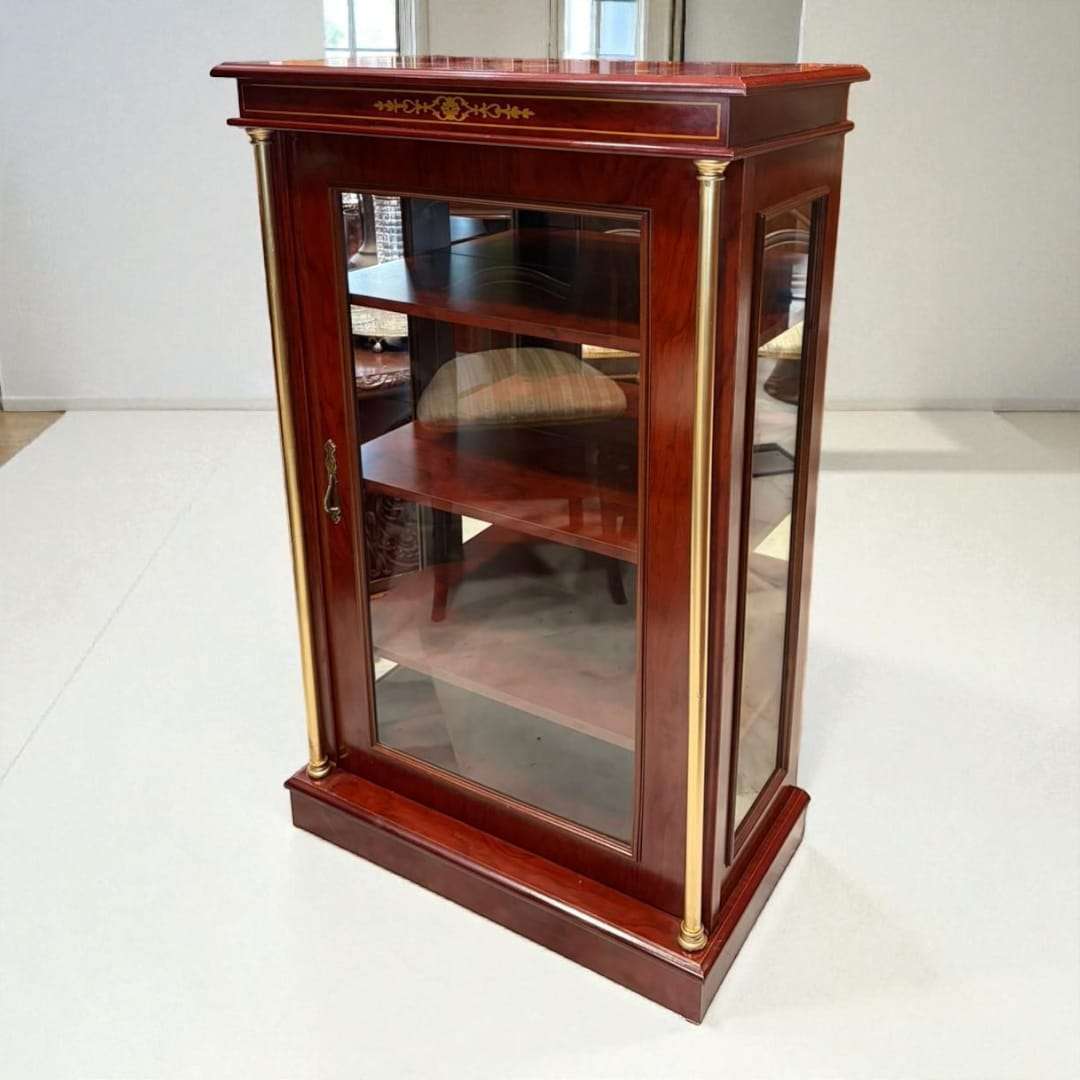 Vitrina expositora de madera con columnas doradas y cristal frontal.