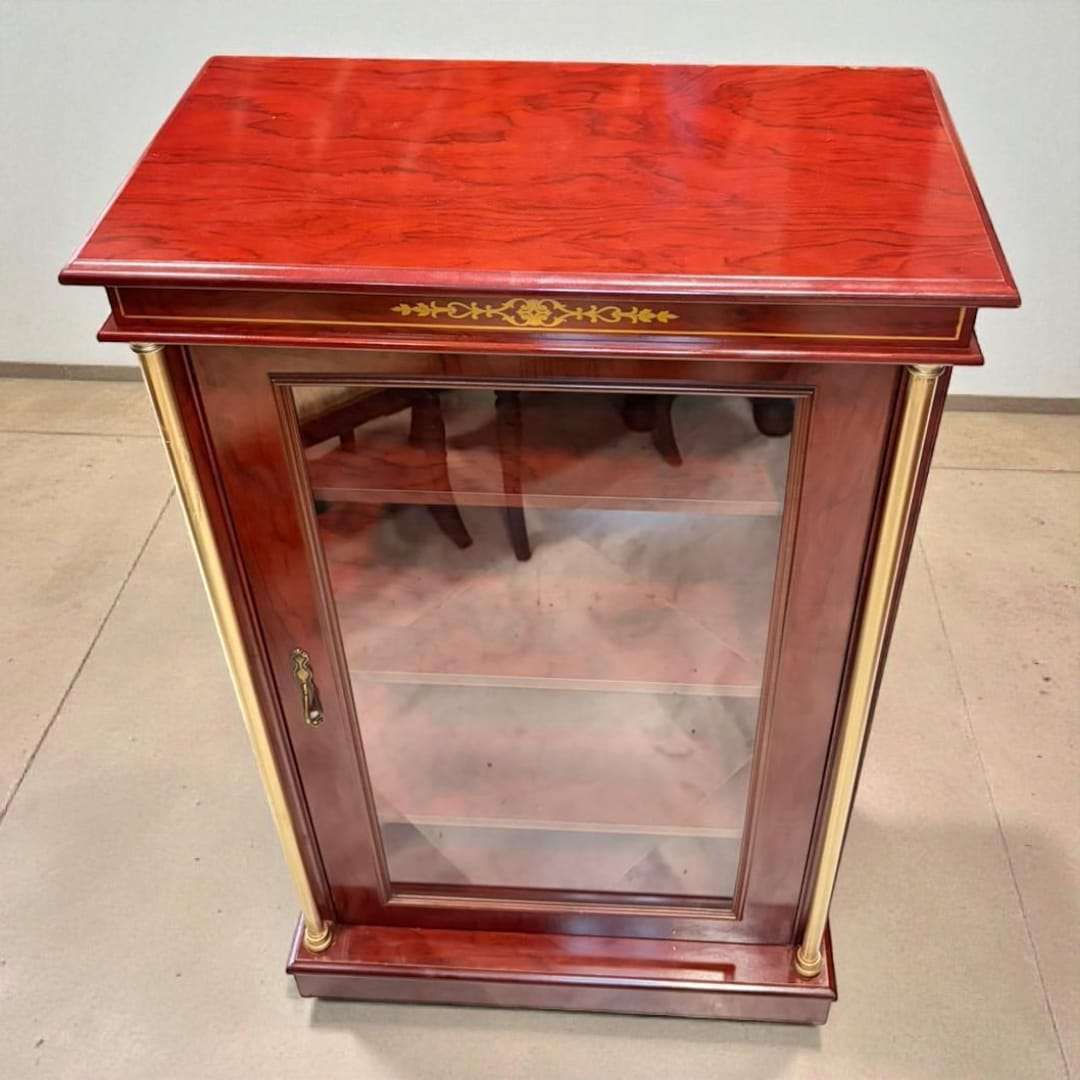 Vitrina expositora de madera con columnas doradas y cristal frontal.