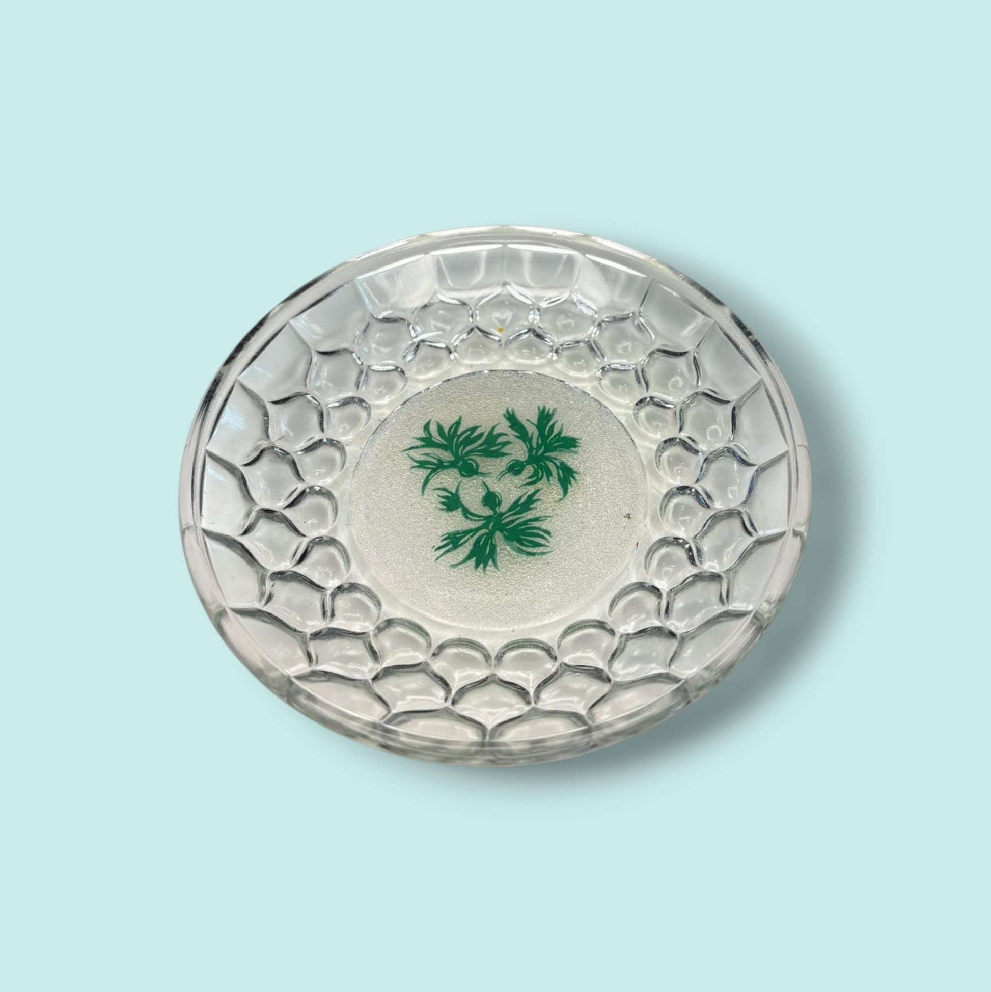 Plato de cristal para aperitivos con diseño en relieve tipo panal y decoración vegetal verde. Ideal para servir canapés con estilo.