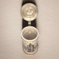 Jarra de cerveza alemana de porcelana con tapa metal abierta, decorada con ilustraciones históricas y texto en latín. Ideal para decoración vintage.