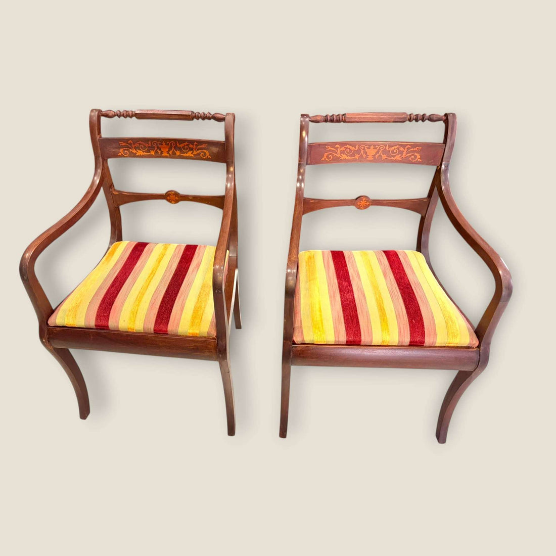 Par de sillones de caoba con taracea y brazos clásicos elegantes, tapizados a rayas rojas, amarillas y naranjas. Ideal para decoración de salón vintage.