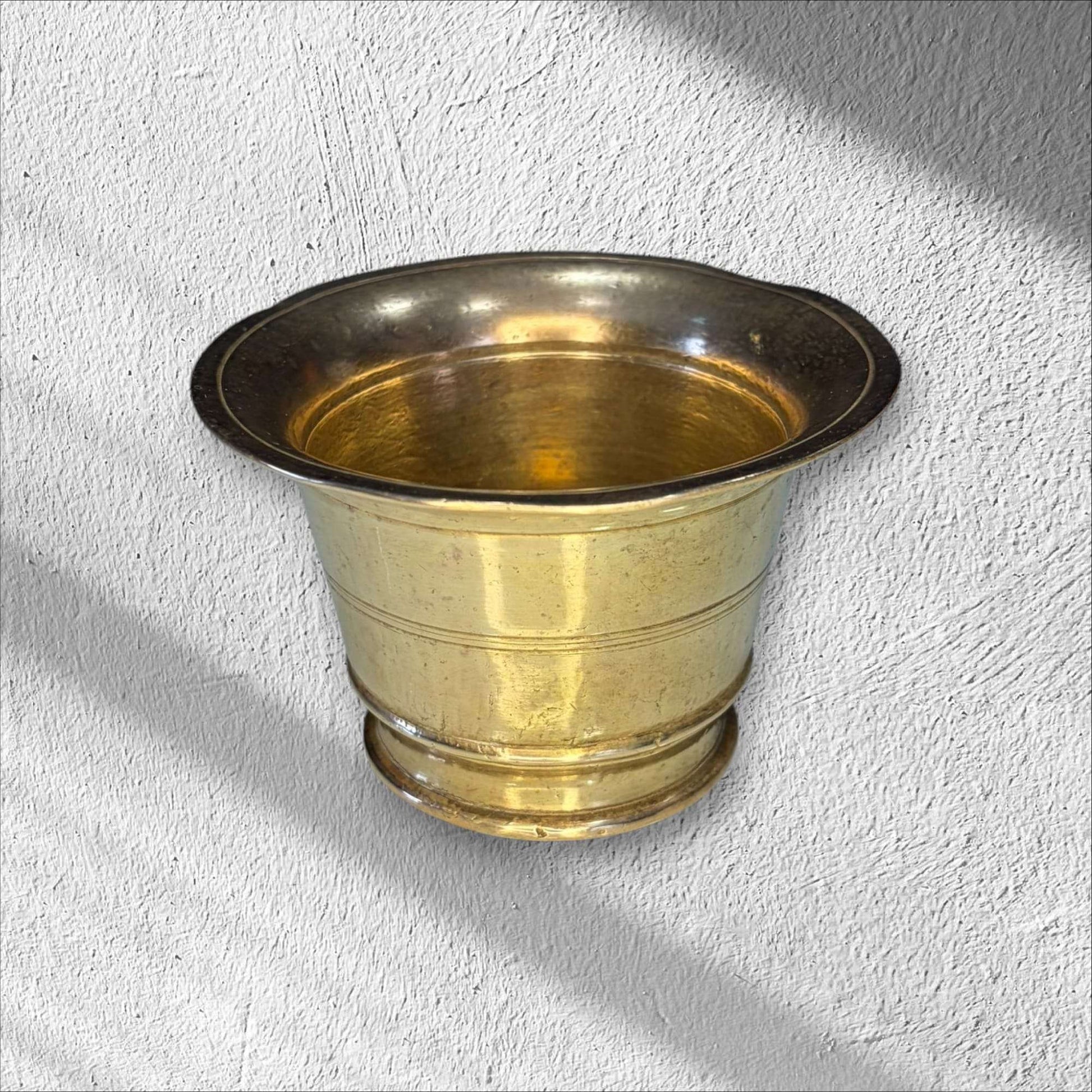 Mortero de bronce antiguo sin maja, acabado brillante y forma cónica, perfecto para decoración rústica en interiores clásicos.